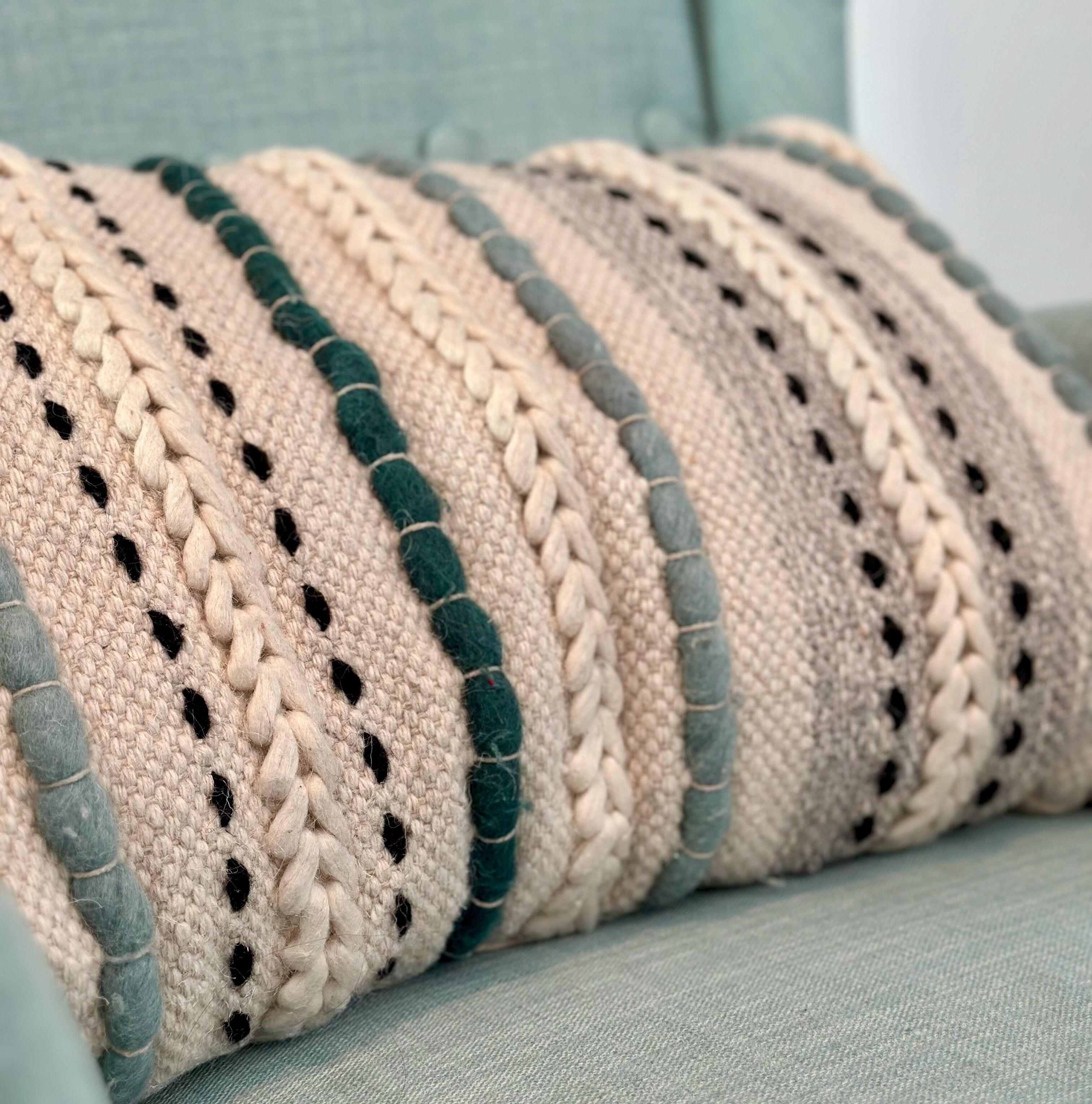 Una coperta all'uncinetto con motivo a righe e dettagli verde scuro.