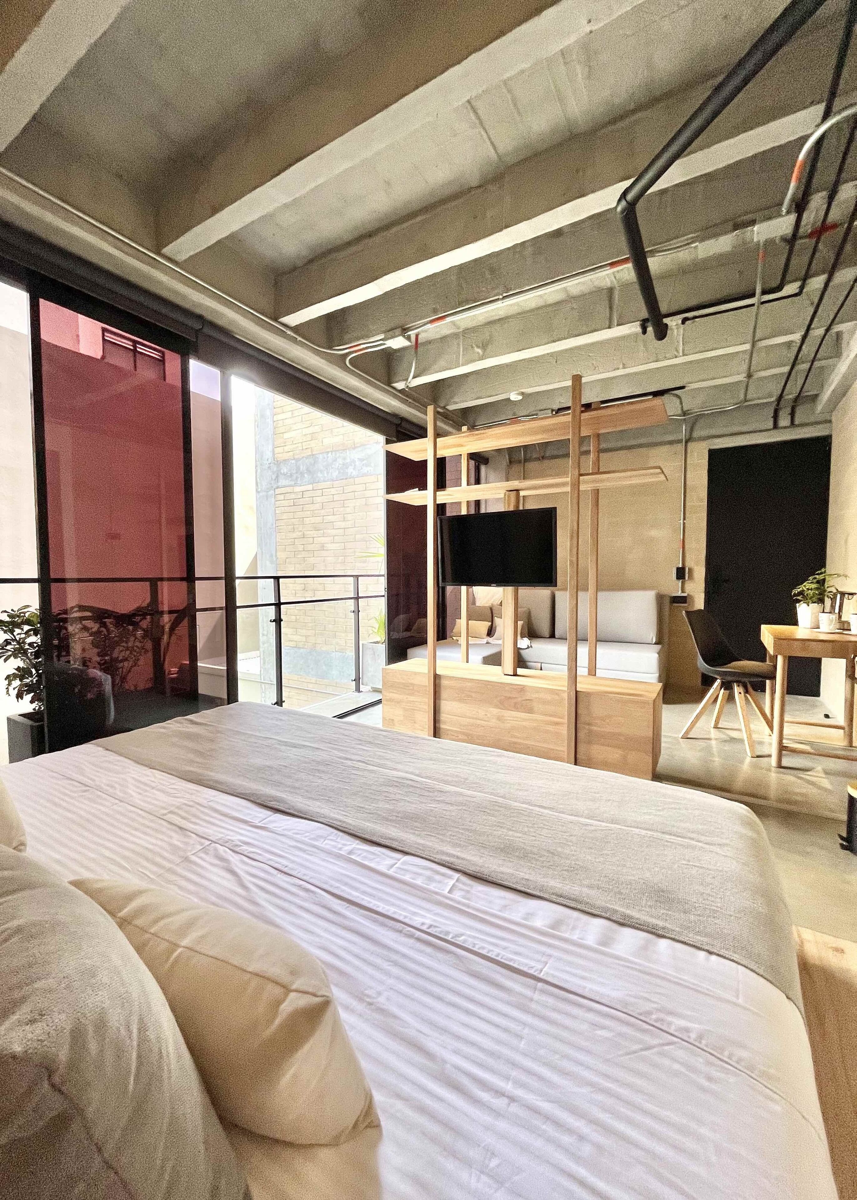 Une chambre moderne avec un grand lit, une télévision et un balcon offrant une vue agréable.