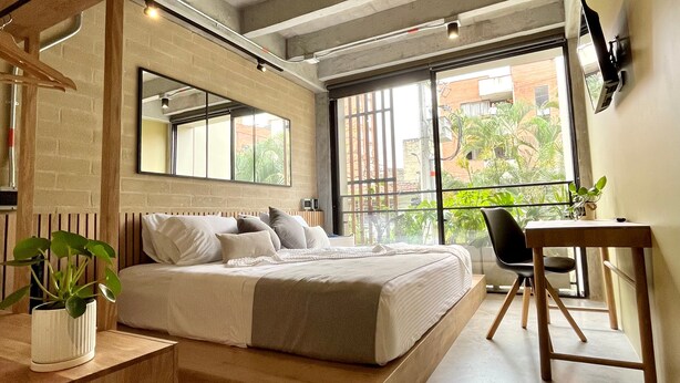 Un dormitorio moderno con cama, mesita de noche, silla y escritorio.