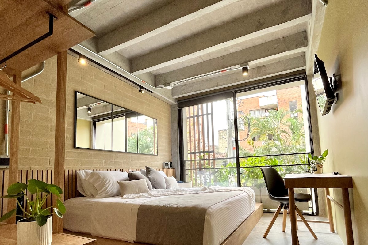 A modern bedroom with a bed, bedside table, chair, and a desk.