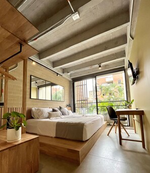 A modern bedroom with a bed, bedside table, chair, and a desk. - beminimal parques (Medellín)