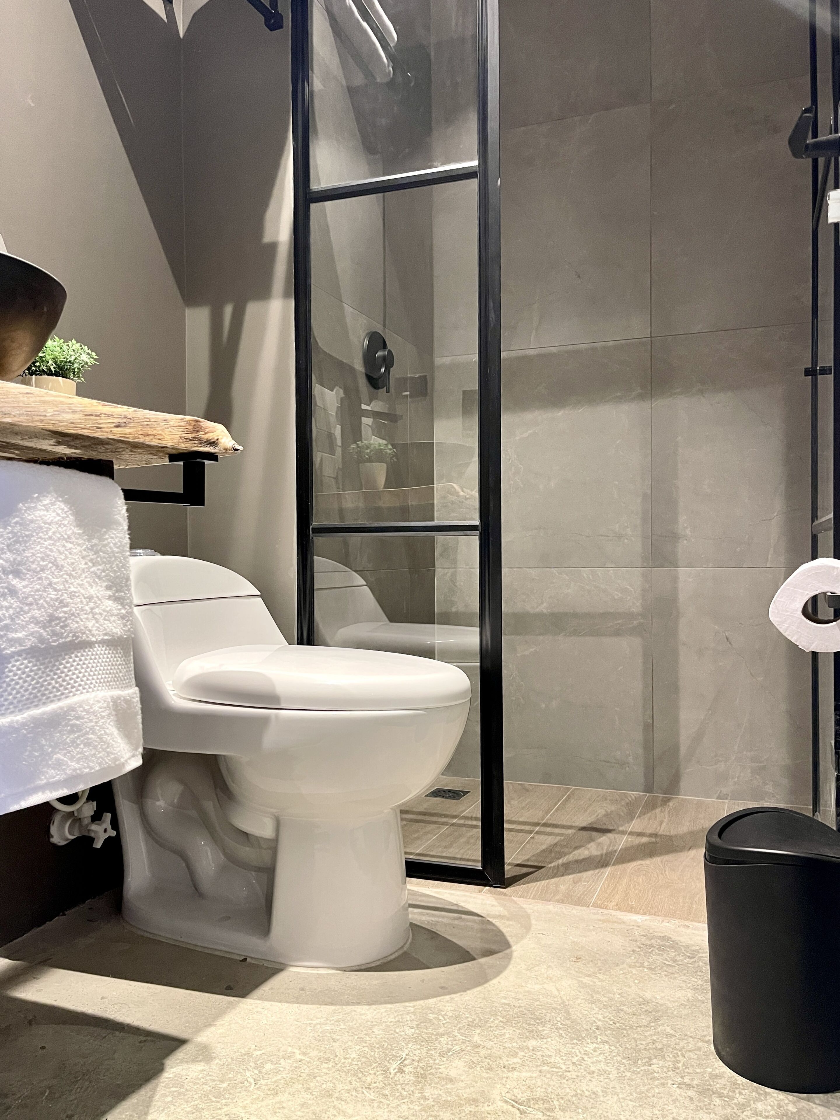 Une salle de bain moderne équipée de toilettes, d’une douche et d’une poubelle.