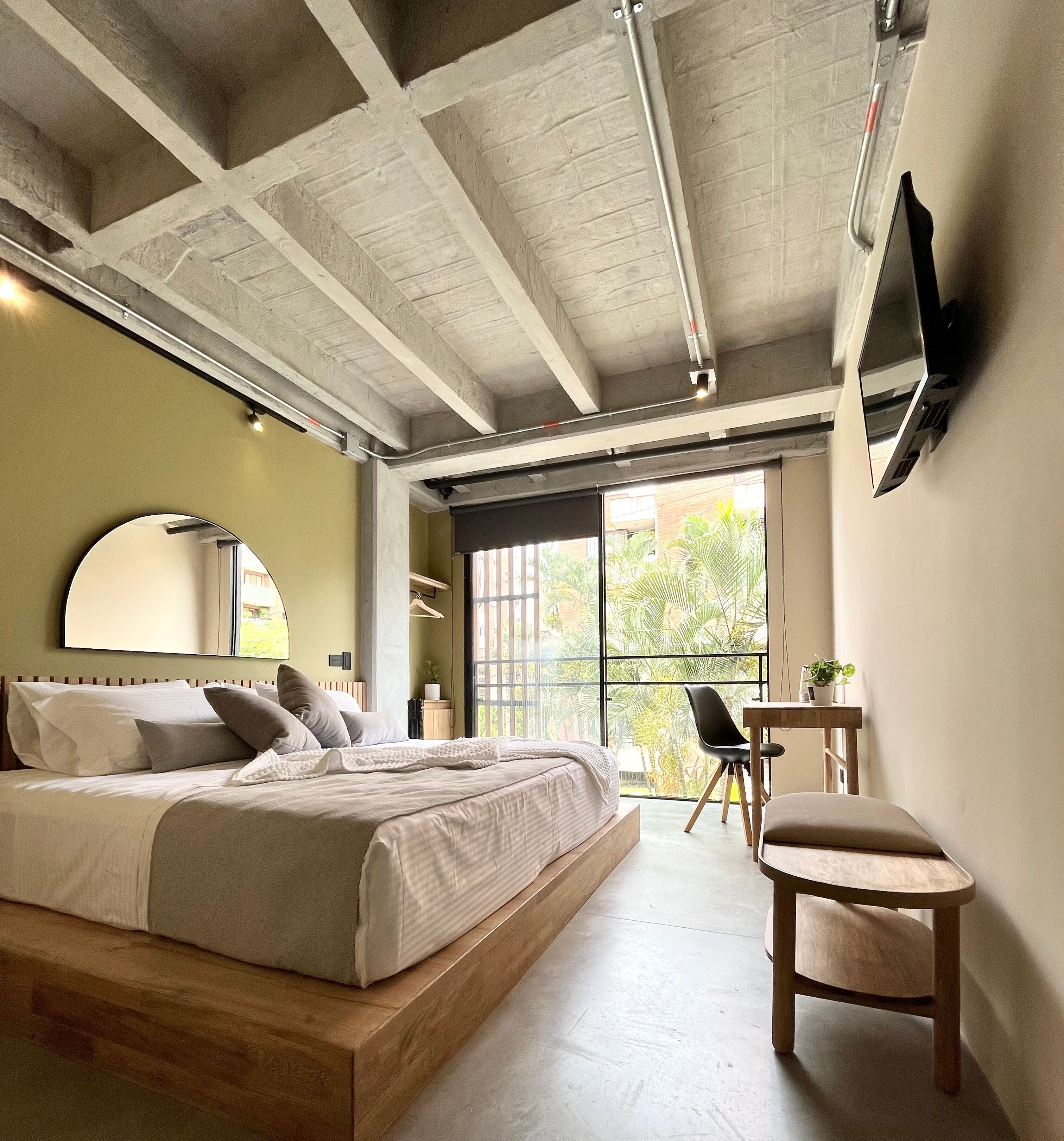 Een moderne slaapkamer met een groot bed, een bureau en een televisie aan de muur.