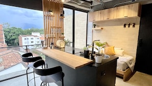 Una cocina moderna con una isla central, taburetes de bar y vistas a la ciudad.