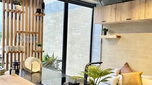 Una cocina moderna con detalles de madera, un salpicadero de vidrio y una zona de comedor con sofá y cojines.