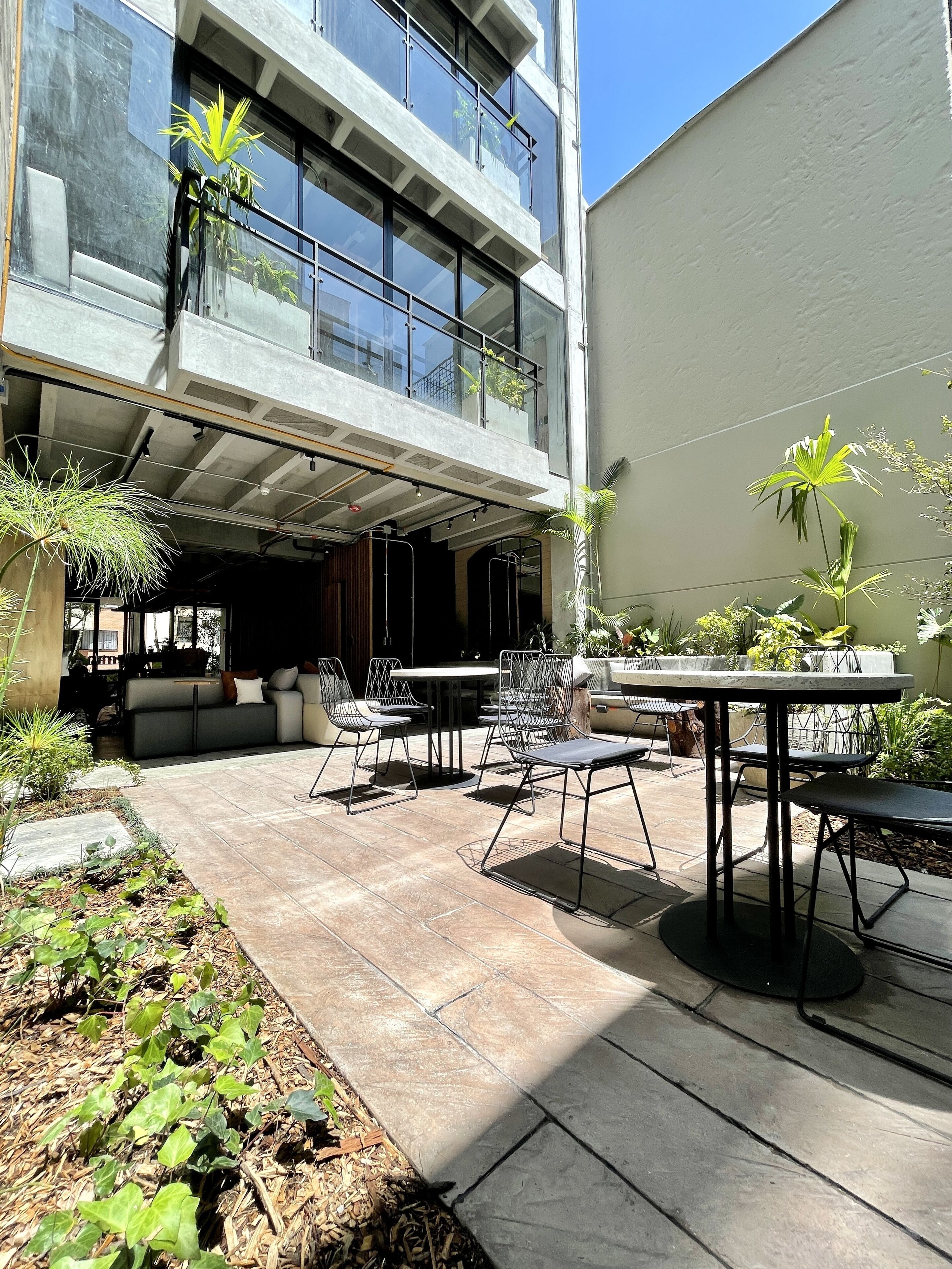 Une terrasse extérieure moderne, aménagée avec un espace repas, des sièges et des plantes en pot.