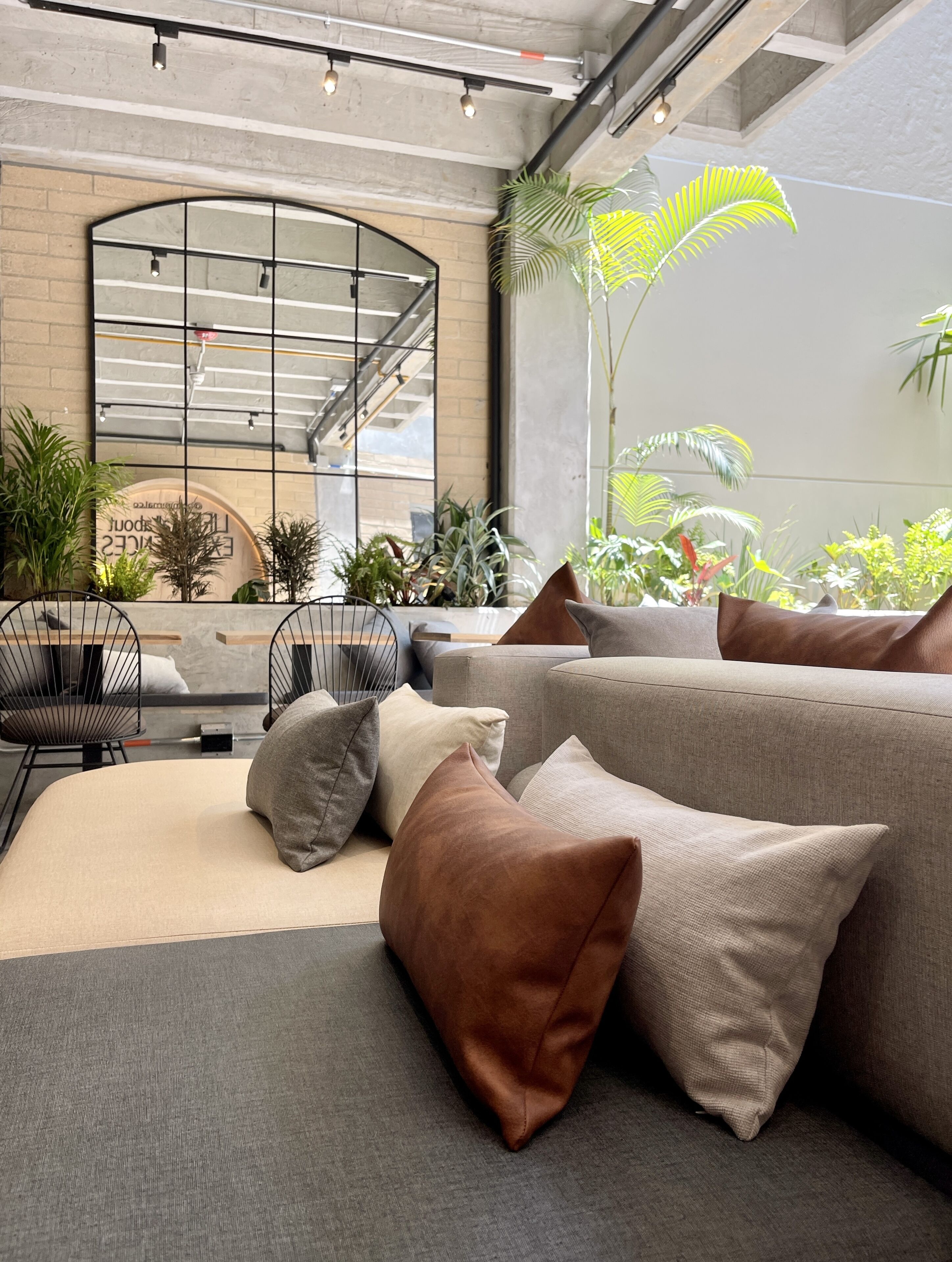 Ein stilvoller Lounge-Bereich mit einer Sofagarnitur, einem Esstisch und Stühlen. Pflanzen und ein großes Fenster sorgen für natürliches Licht.