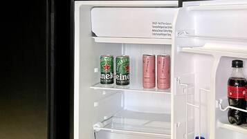 A kitchen with a microwave, a refrigerator, and a shelf above the microwave.