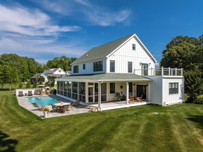 A large house with a swimming pool, covered patio, and a fenced yard.