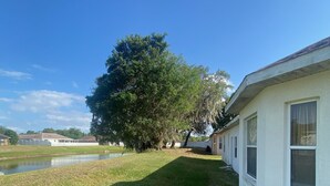 A residential area with a grassy lawn, a large tree, and a white building with multiple windows. - Three bedrooms, full kitchen, clean, quiet and relaxing. (St. Cloud)