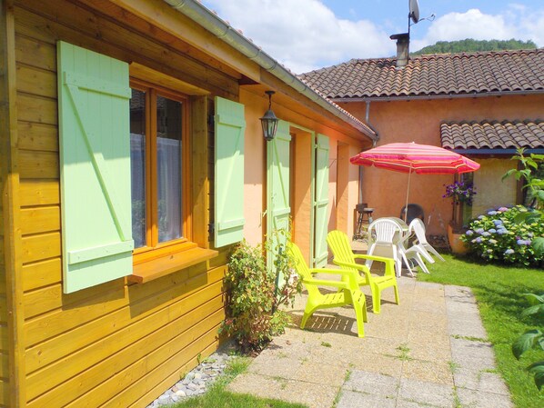 A wooden building with green shutters, outdoor seating, and a garden. - Gite in the mountains (Seix)