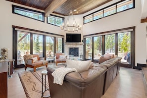 Relax in a spacious living area with expansive views of the surrounding landscape, a cozy fireplace, and comfortable seating.