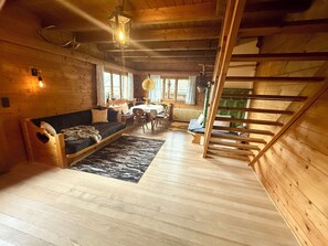 A cozy log cabin interior with a loft bedroom, wooden floors, and a dining area. - In the middle of the Bödele skiing and hiking area (Schwarzenberg)