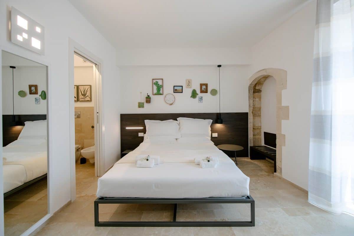 Ein modernes Schlafzimmer mit einem großen Bett, Nachttischen, einem Spiegel und Kunstwerken an den Wänden.