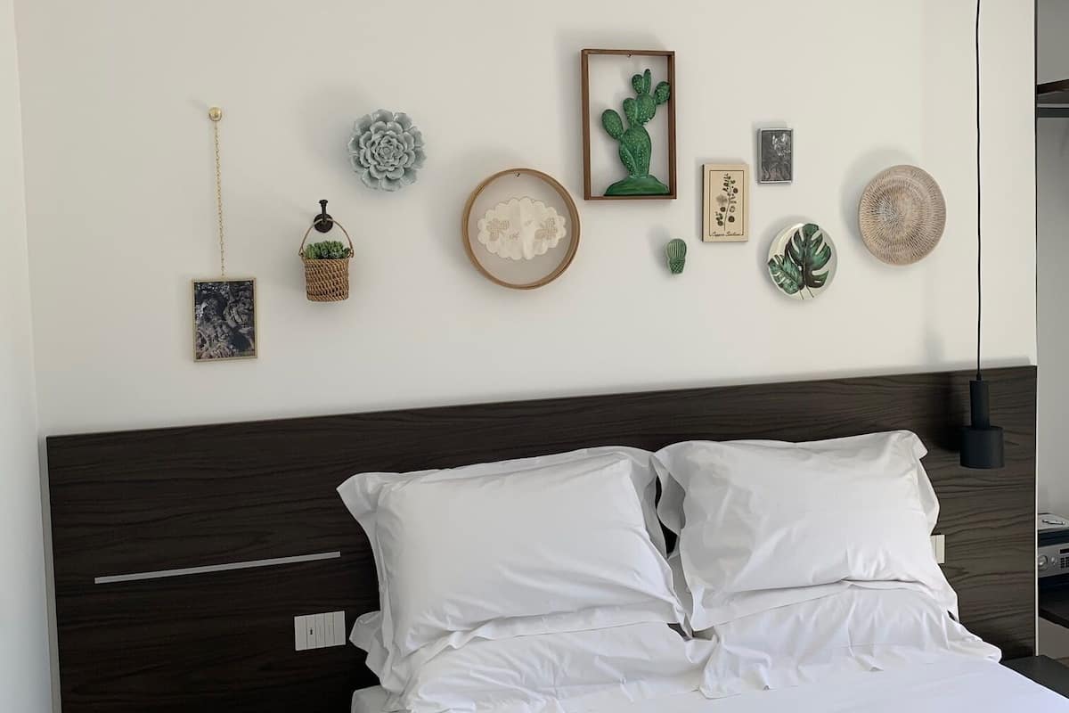 Ein ordentlich bezogenes Bett mit weißen Leinen, ein dunkles Holz-Kopfteil und ein kleiner runder Tisch daneben.
