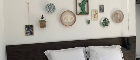 A neatly made bed with white linens, a dark wood headboard, and a small round table beside it.