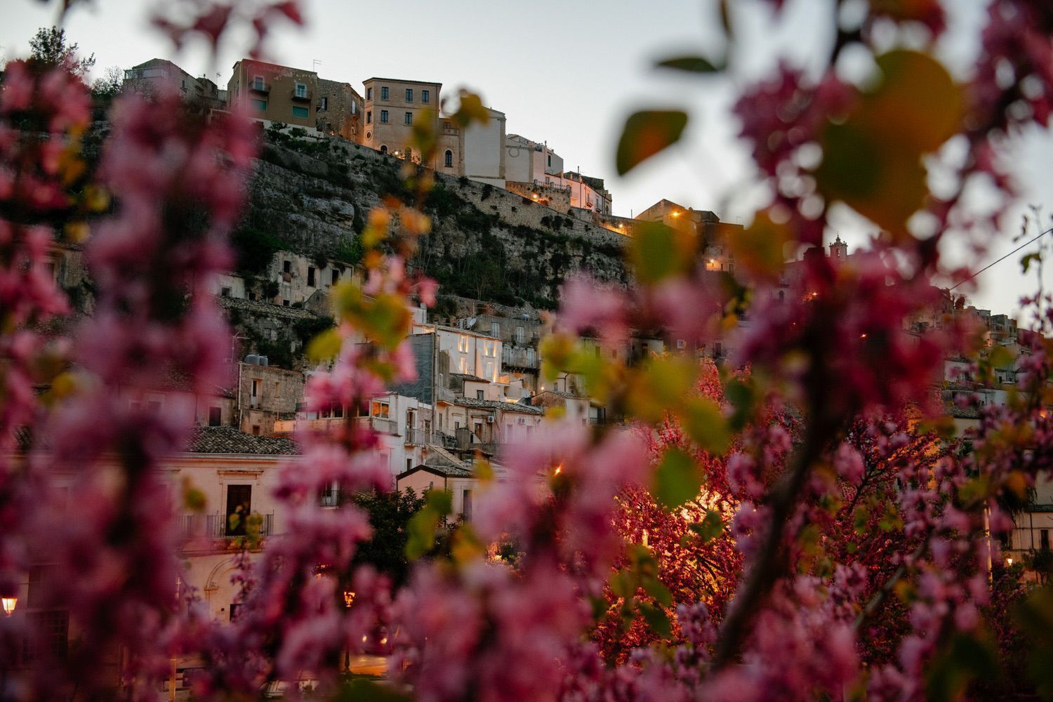 A hillside town with buildings built on a slope, featuring a mix of residential and possibly commercial structures.