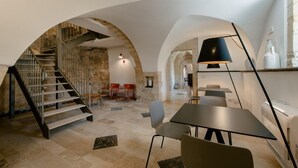 Un interior moderno con una escalera, zona de estar y mesas.