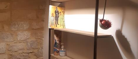 A shelf with a book, a bottle, and a decorative item against a brick wall.