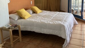 A bedroom with a bed, a nightstand, a chair, and a view of the outside. - Quiet sea view on the hill of Peñiscola (Peniscola)