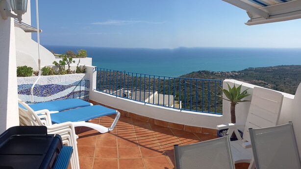 A terrace with a view of the sea, white lounge chairs, and a tiled floor. - Quiet sea view on the hill of Peñiscola (Peniscola)