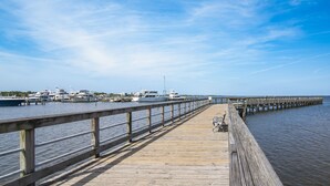A wooden pier extending into calm water with boats docked at the end.