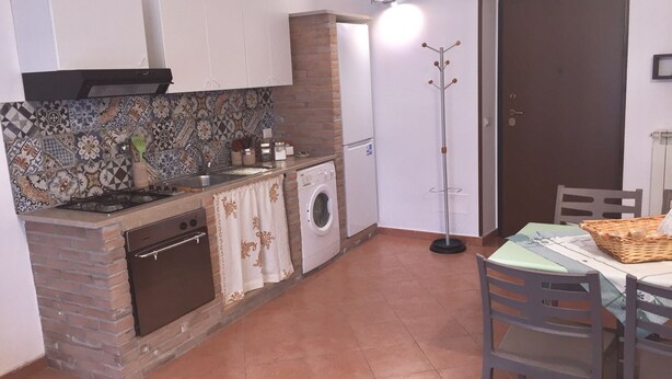 A compact kitchen with a stove, oven, and washing machine, a dining area with a table and chairs, and a patterned backsplash. - Hola Cathedral House (Palermo)