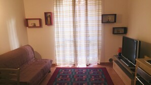 A living room with a sofa, a TV on a stand, a patterned rug, and curtains. - Hola Cathedral House (Palermo)