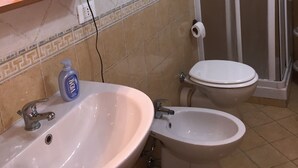 A bathroom with a sink, bidet, toilet, and a shower enclosure. - Hola Cathedral House (Palermo)
