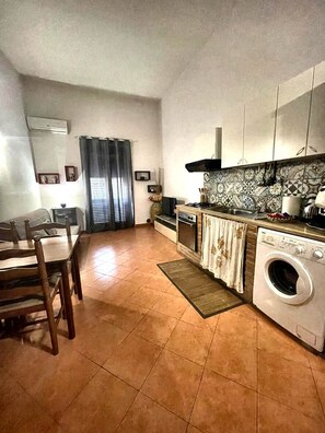 A compact kitchen with a dining area, a washing machine, and a tiled backsplash. - Hola Cathedral House (Palermo)