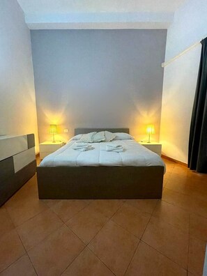 Ein Schlafzimmer mit einem großen Bett, zwei Nachttischen und Lampen.