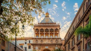 A street leading to a building with a prominent archway and a dome. - Hola Cathedral House (Palermo)