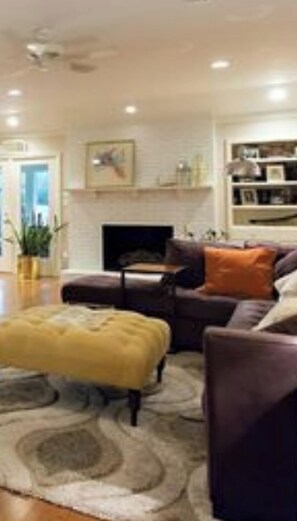 Un salon avec un canapé, un pouf et une cheminée.