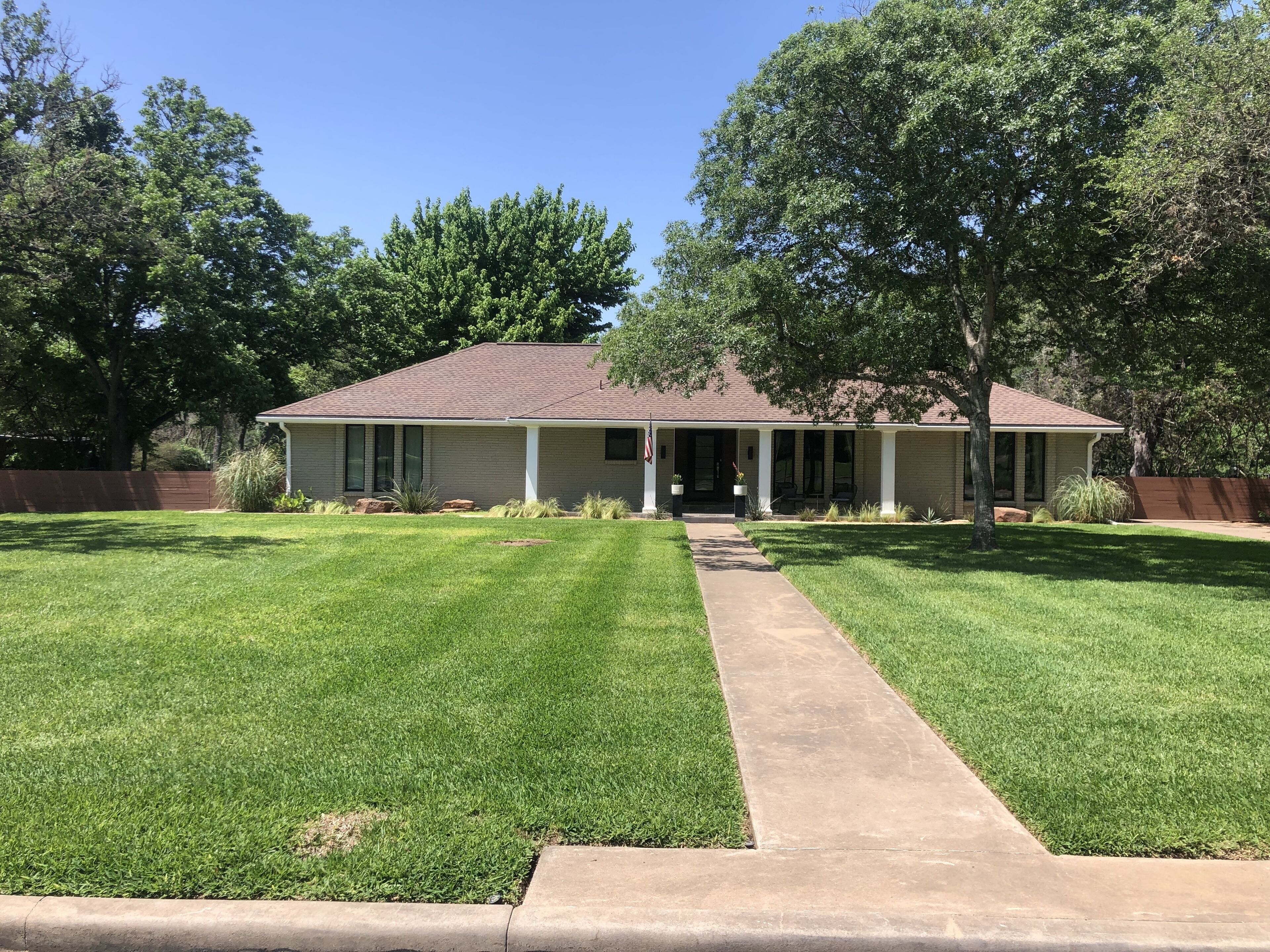 A single-story house with a front porch, a lawn, and a pathway leading to the entrance.