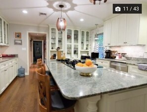 Enjoy cooking in this well-equipped kitchen with a central island, featuring a bowl of fresh fruit and modern appliances.