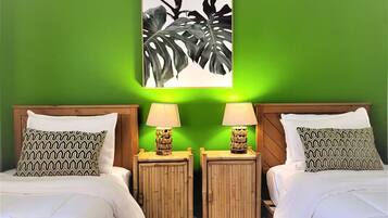 A room with two beds, green walls, and a framed artwork above the beds.