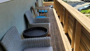 A wooden deck with wicker furniture, including chairs and a round table.