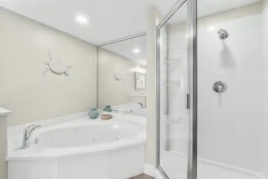 Een bad/douchecombinatie, een bubbelbad, een haardroger, handdoeken