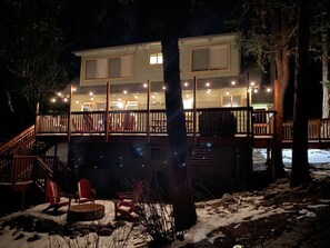Ein zweistöckiges Gebäude mit einer Terrasse, Holzgeländern und Außenmöbeln.
