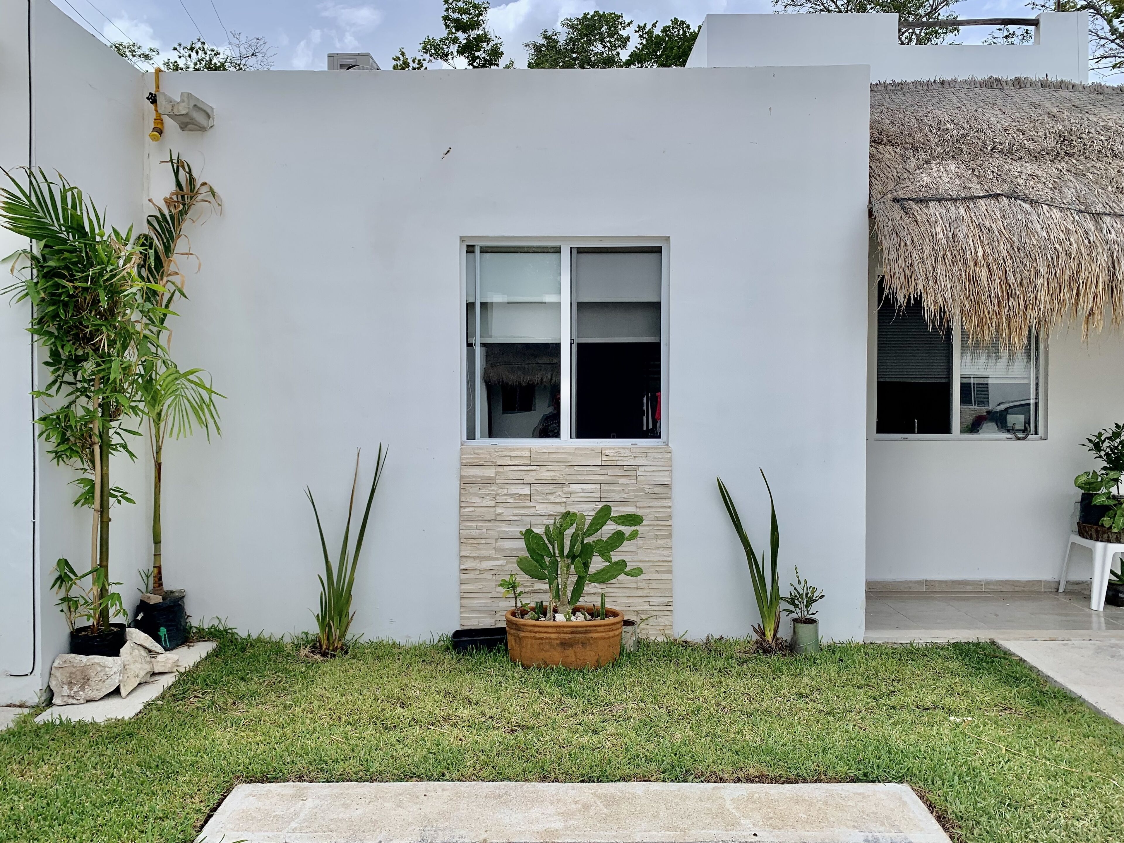 A modern building with a white exterior, a large window, and a thatched roof.