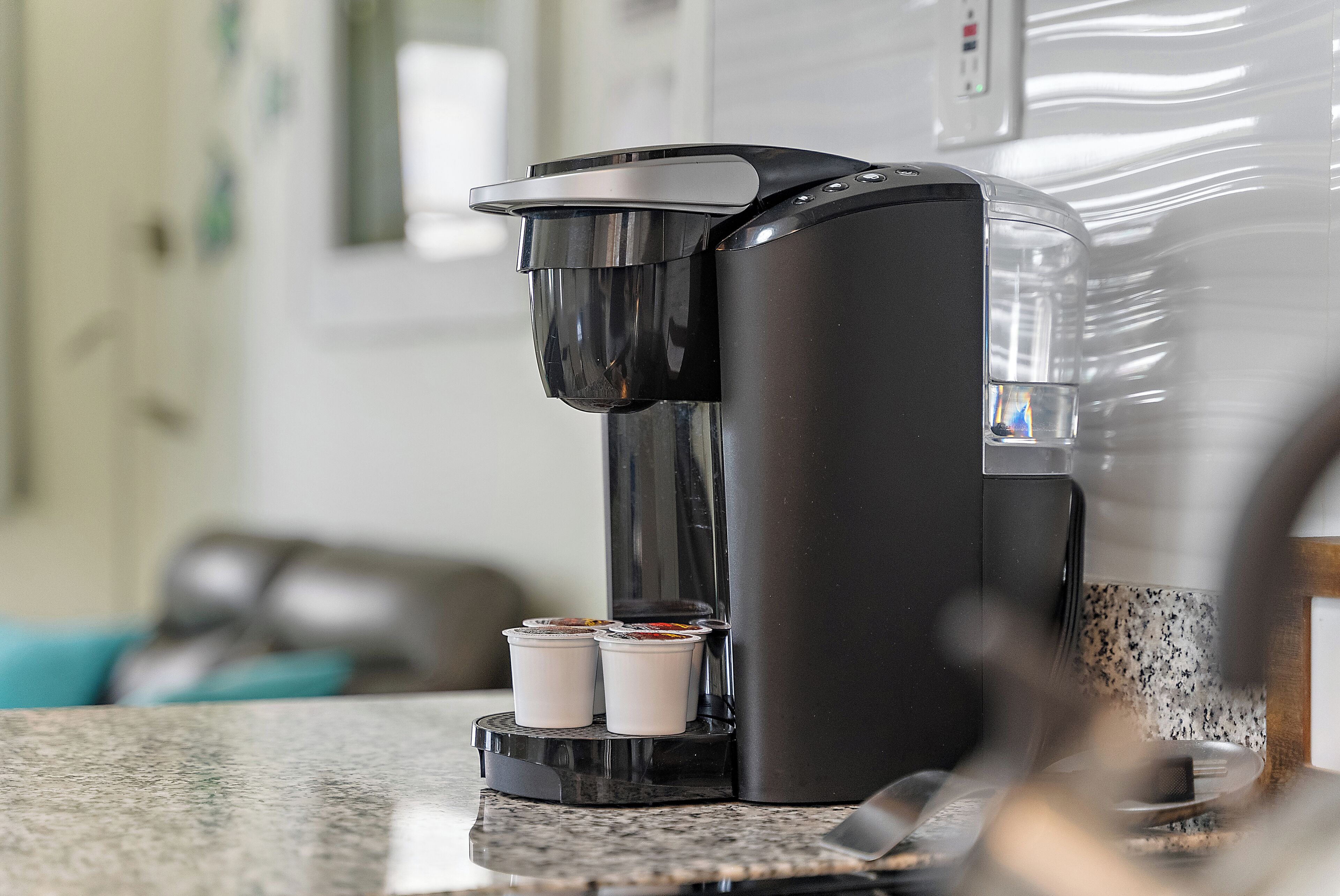 A coffee maker with two disposable cups on a kitchen counter.