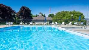Une piscine à l’eau d’un bleu limpide, entourée de chaises longues et d’une clôture.