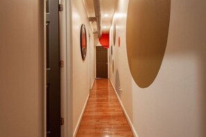 A hallway with wooden flooring, white walls, and a door at the end. - Colorful & Quirky 2-BR Loft w/Private Deck | MICA, JH & UMMC (Baltimore)