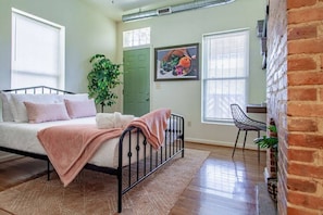 Un dormitorio con una cama, una puerta verde, una planta y una silla.