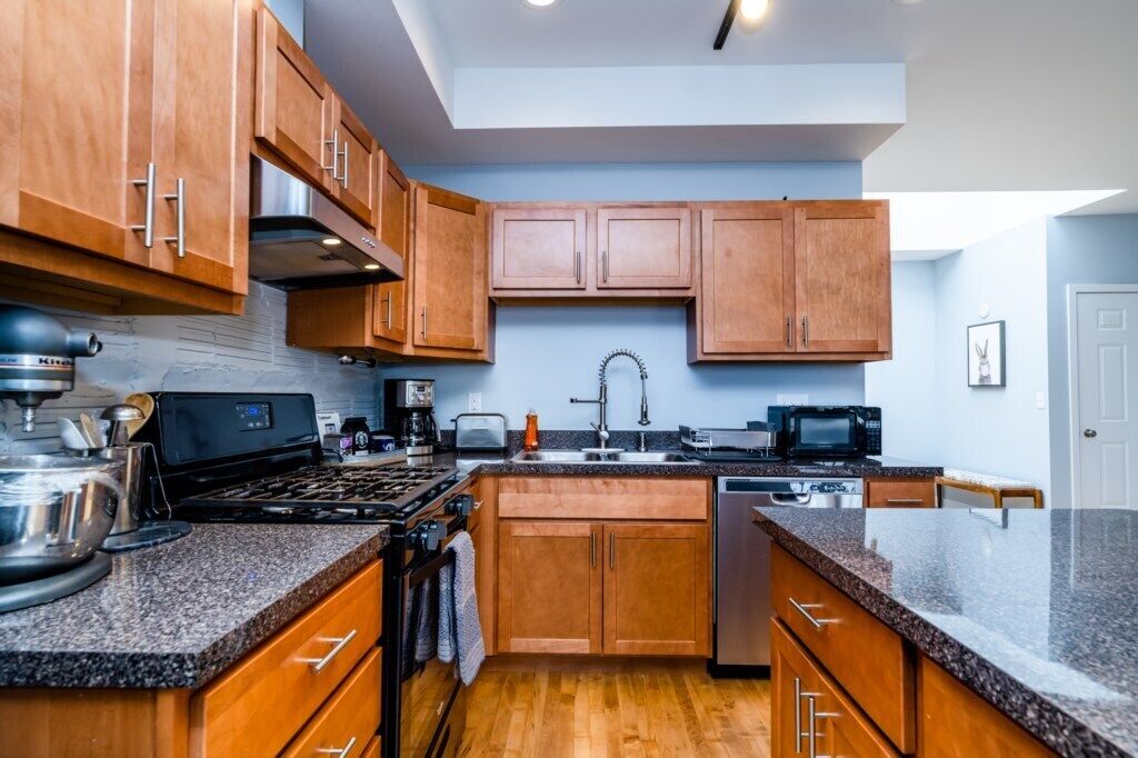 A modern kitchen with wooden cabinets, granite countertops, a gas stove, a microwave, and a sink.