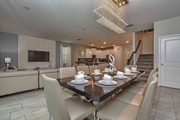 A modern dining area with a dark wooden table set for six, surrounded by beige chairs. - Sleeps 23 | Avengers Game Room | Themed Rooms | Pool & Spa | Near Disney-1690ST (Kissimmee)
