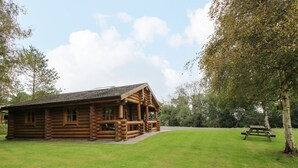 A log cabin with a porch and a picnic table in a grassy area. - Brynallt Country Park (Ellesmere)