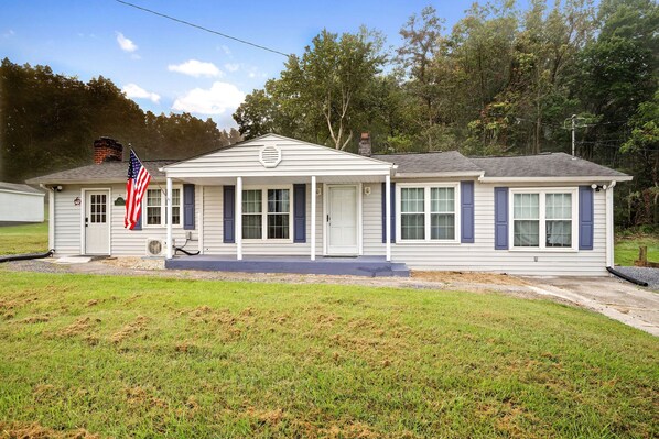 A single-story house with a front porch, a chimney, and an American flag.