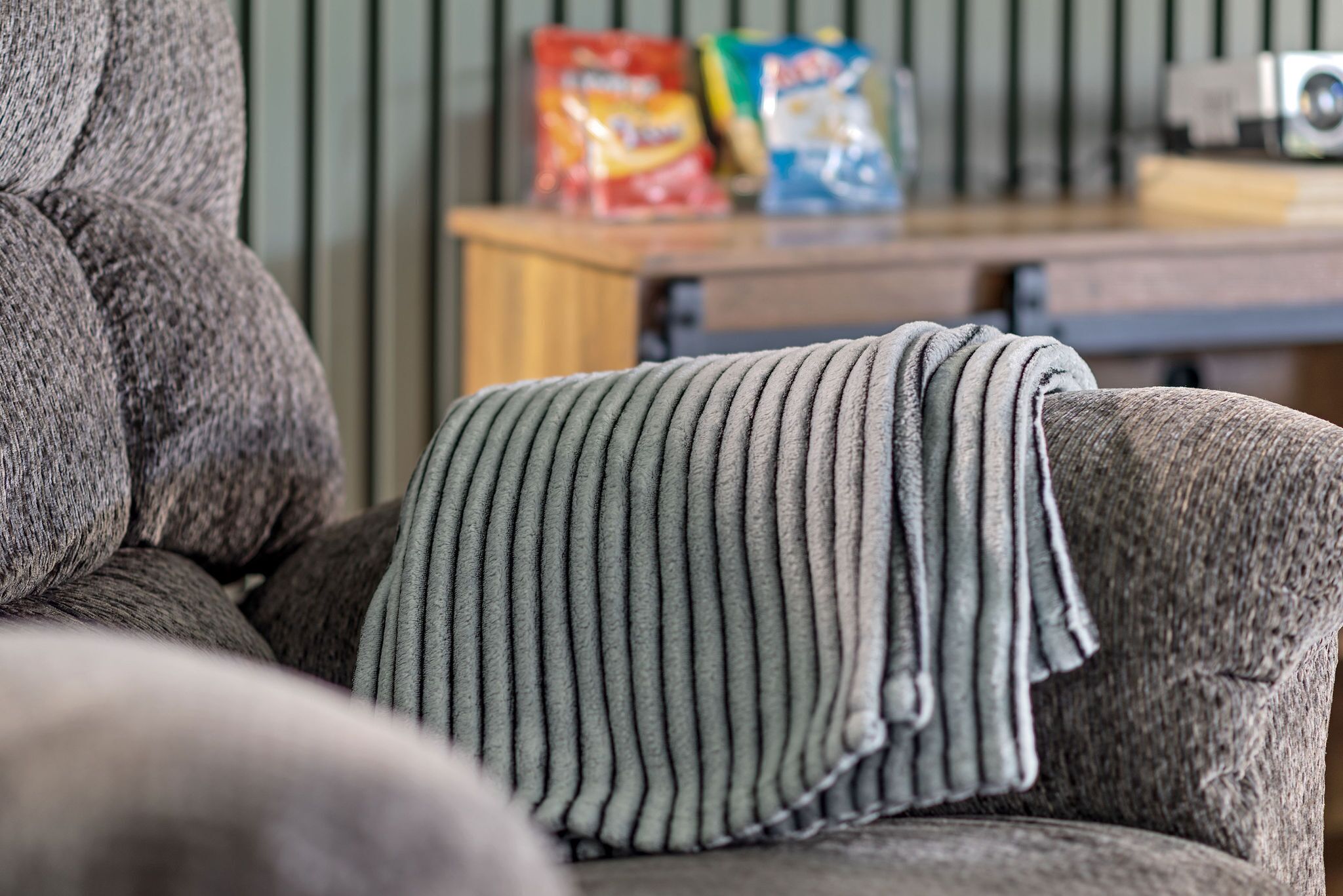 Un sillón tapizado en gris con una manta a rayas.