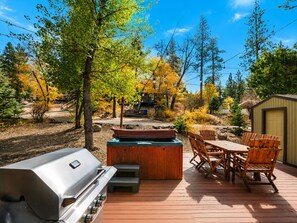 Eine Terrasse im Freien mit Grill, Whirlpool und Holzstühlen.